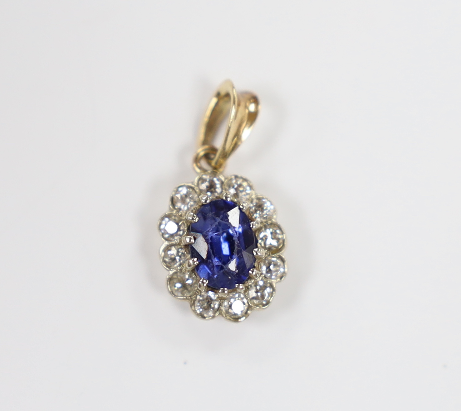 A yellow metal, synthetic sapphire and diamond set oval cluster pendant, overall 19mm, gross weight 1.5 grams.